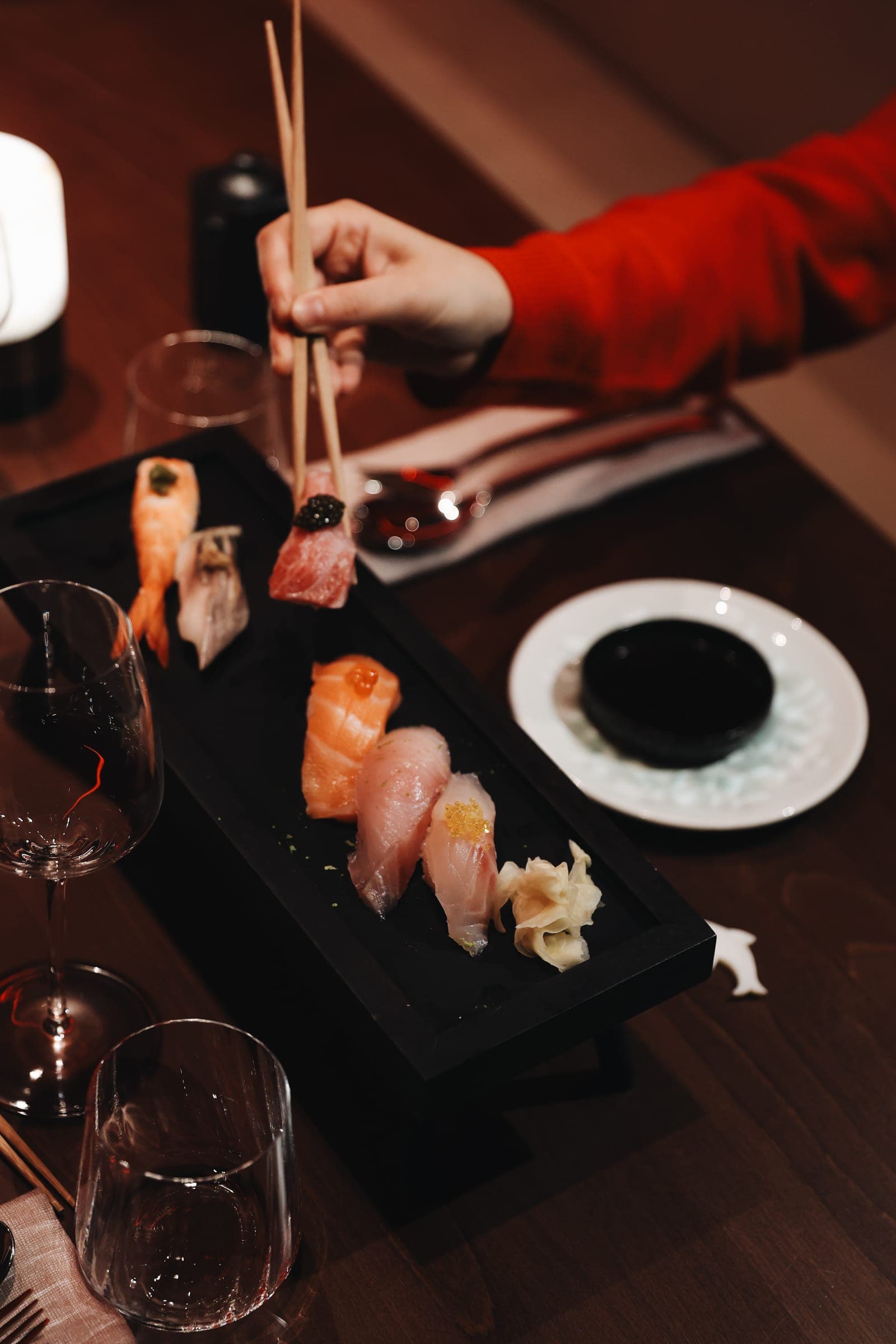 Nigiri-Brett mit Lachs und Thunfisch, mit Stäbchen gegessen